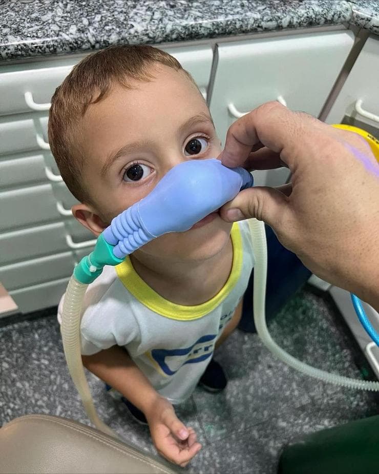 Criança tranquila utilizando a máscara de sedação consciente durante atendimento na Odontossauro